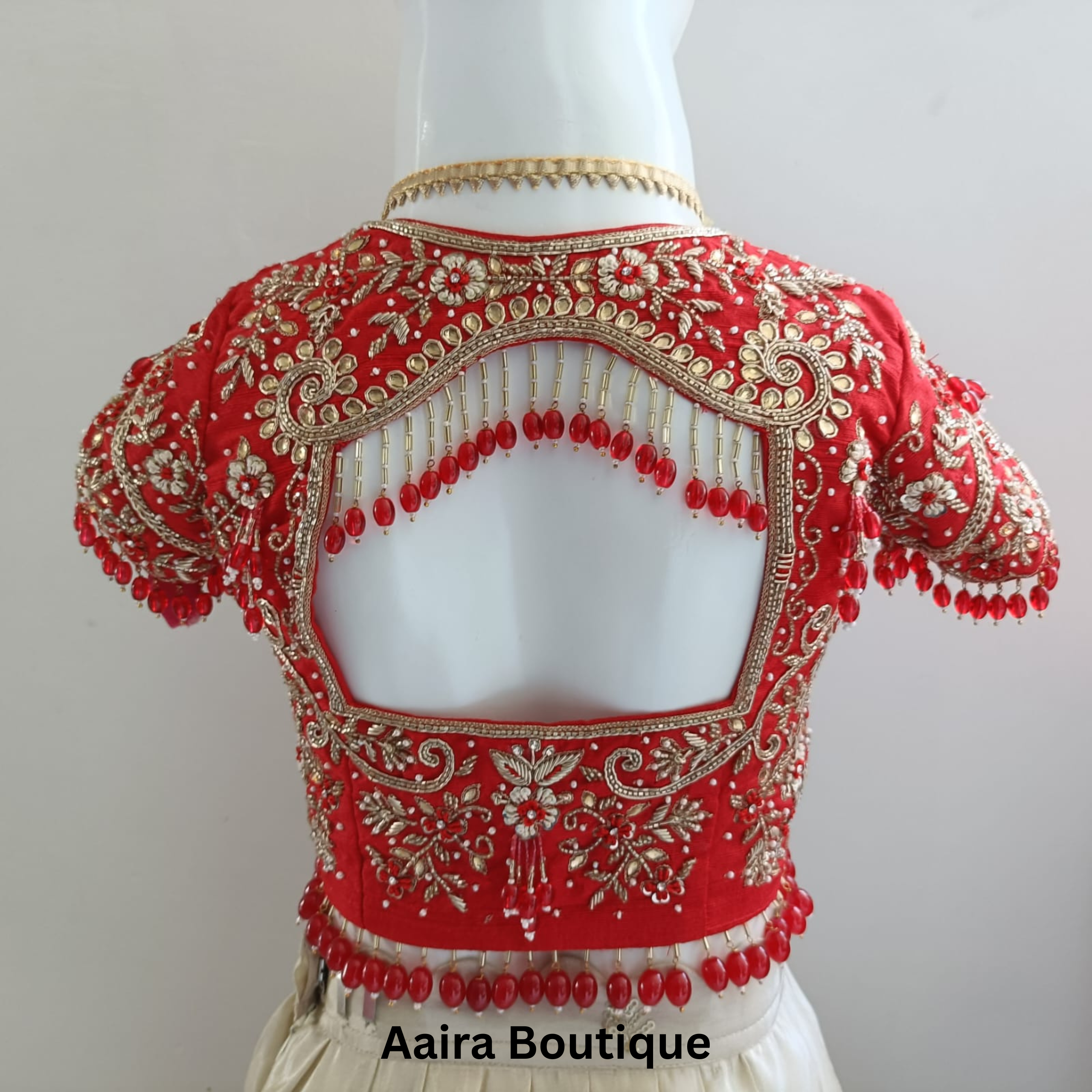 Projects 24 Red bridal blouse with intricate gold embroidery and red beaded tassels on a cut-out back, representing custom bridal wear projects.